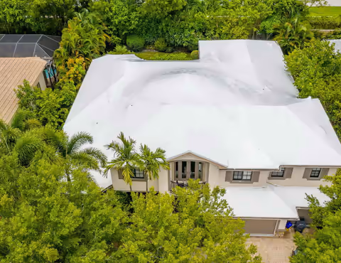 Aerial view of a house with its whole roof wrapped in white shrink wrap